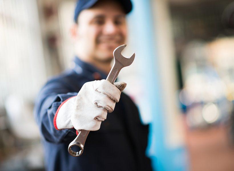 Mecánico en el taller con una herramienta llave en la mano.